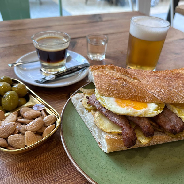 Esmorzar valencià: entrepà d'ou ferrat, llonganissa i creïlles, amb olives, cacaus, cafè i cervesa