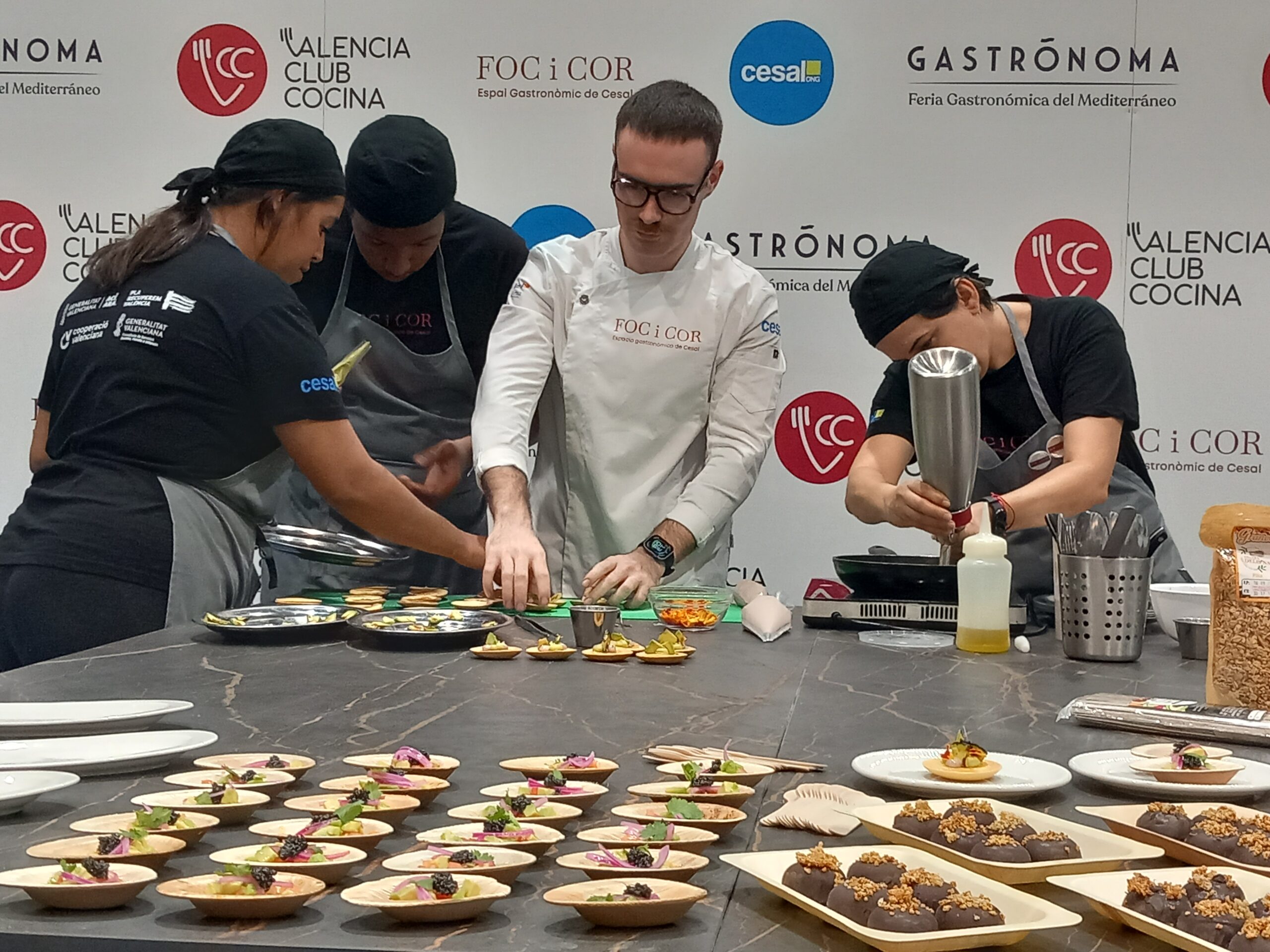 el profesor de Foc i Cor y tres alumnas preparan los platos del evento