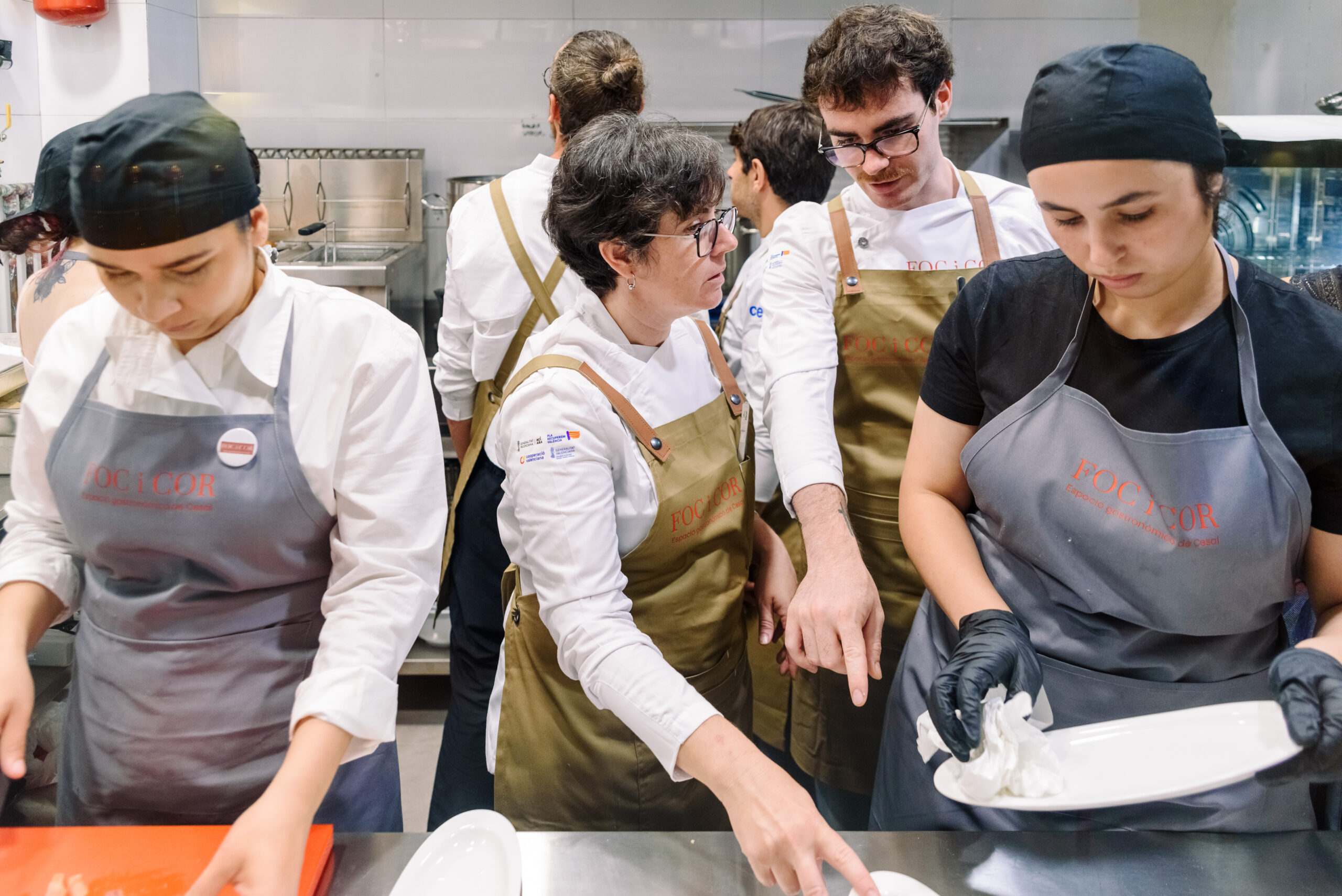 docentes y alumnado preparan comida en la cocina del restaurante